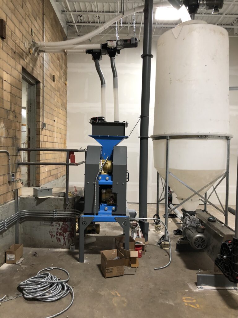 RMS Roller Mill sits on a concrete floor next to a silo.